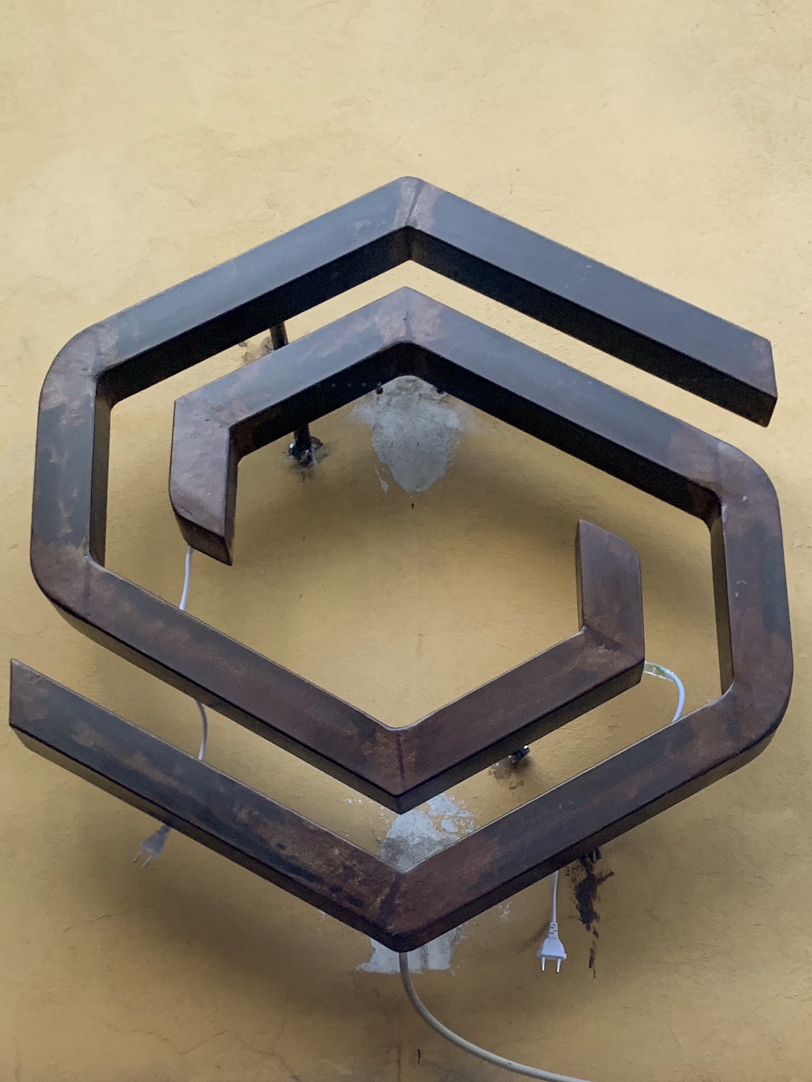 Ornate wrought iron shop sign with elaborate scrollwork and decorative patterns