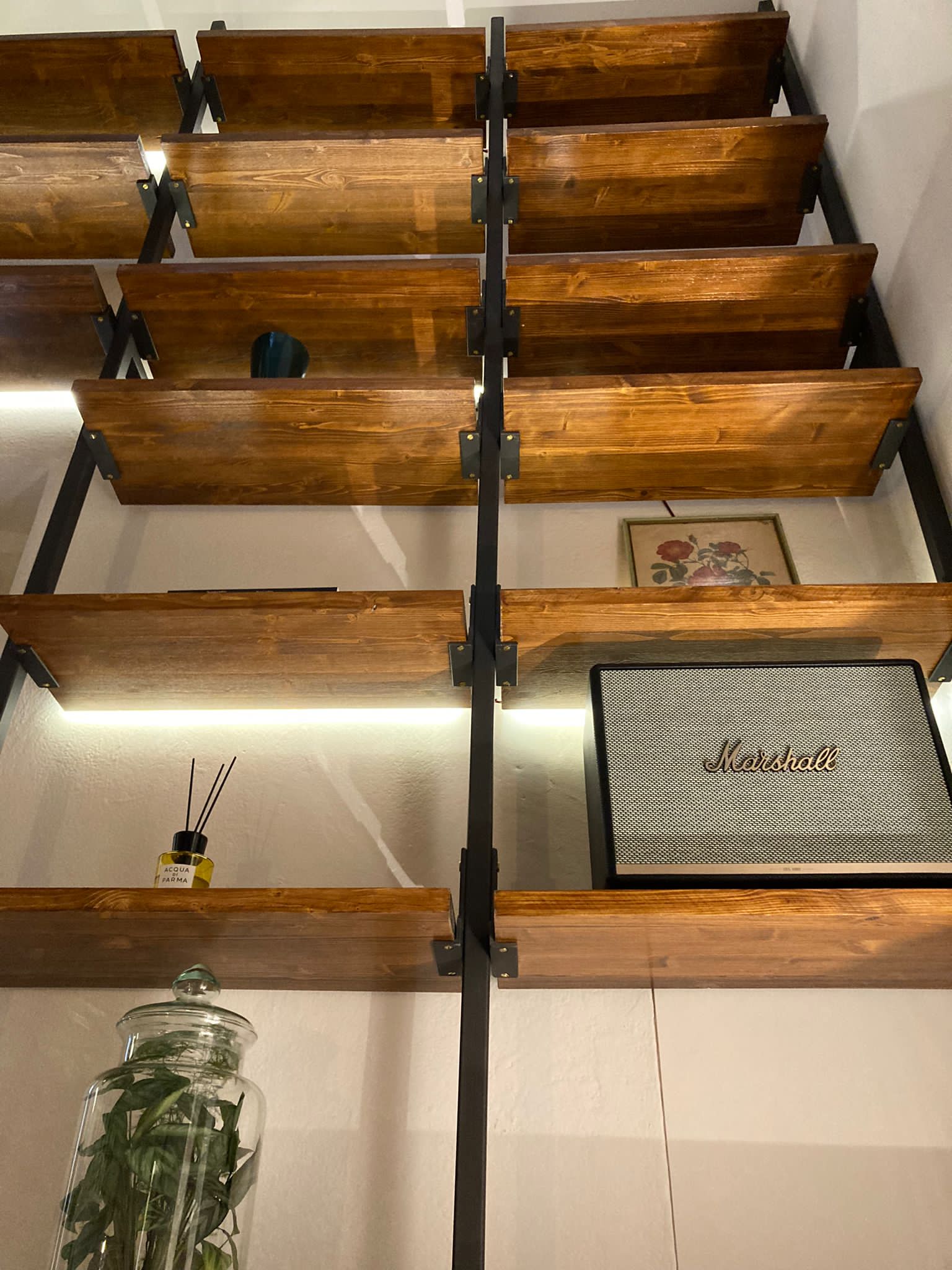 Wall-mounted shelving system with black metal brackets and wooden shelves, LED strip lighting